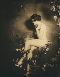 nude woman seated on a ivy drapped swing with a large glass ball